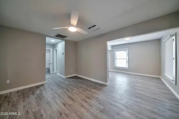 a view of an empty room with wooden floor and a window