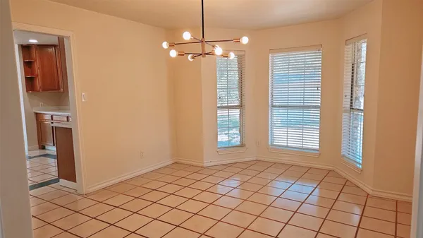 a view of an empty room with window and cabinet area