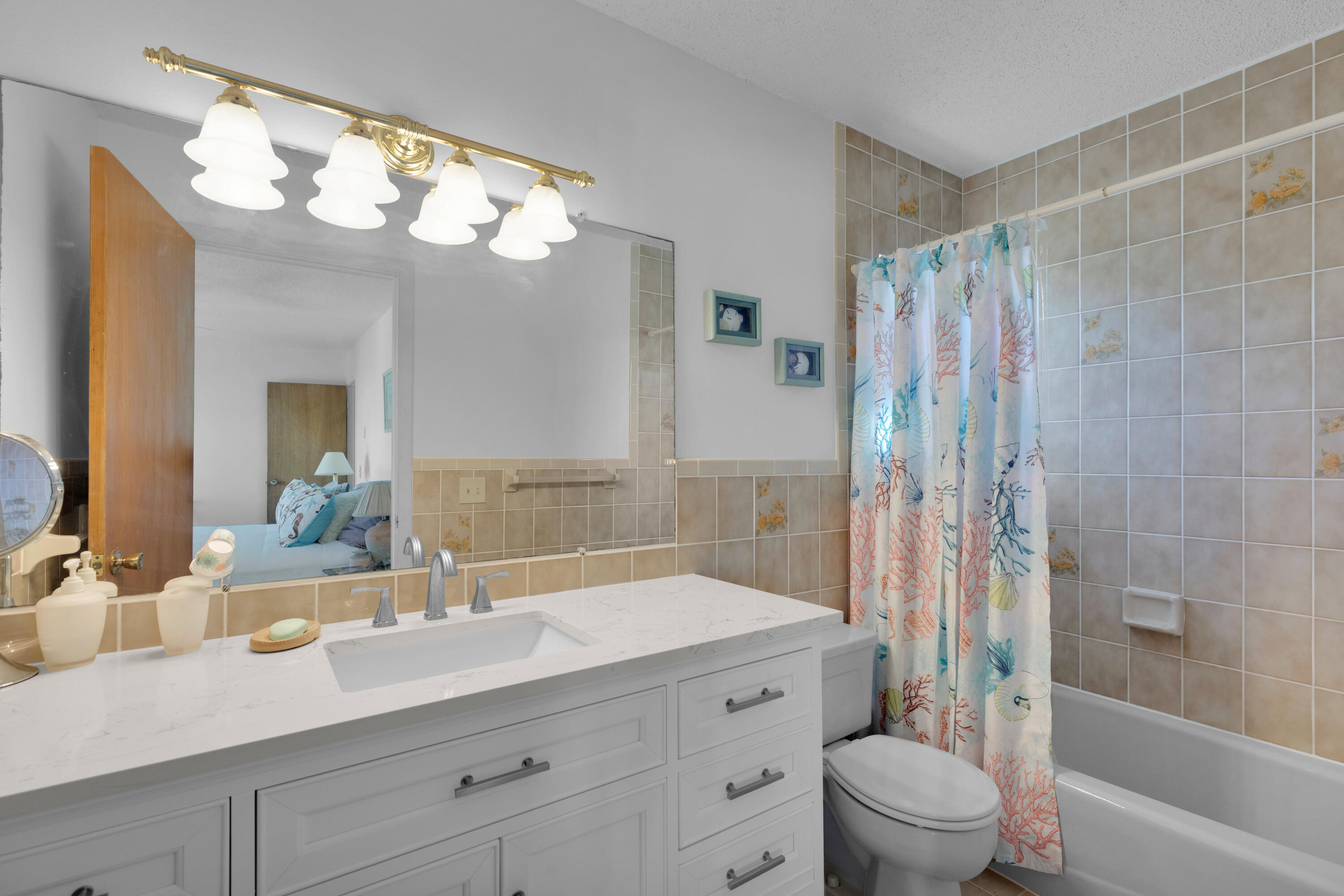 300 3rd Street Key Colony Beach, FL 33051 - Photo 8 of 51 a bathroom with a granite countertop sink a toilet a mirror a vanity a bathtub and shower