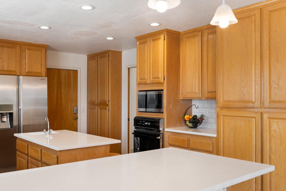 9930 Calvine Road Sacramento, CA 95829 - Photo 15 of 97 a kitchen with stainless steel appliances kitchen island granite countertop a refrigerator a stove and a sink with wooden floor