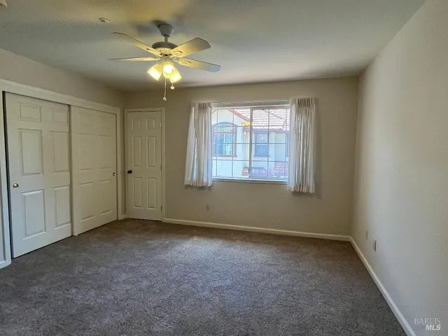 an empty room with fan and windows