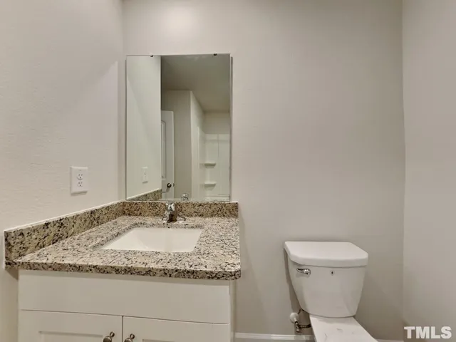 a bathroom with a granite countertop toilet and a sink