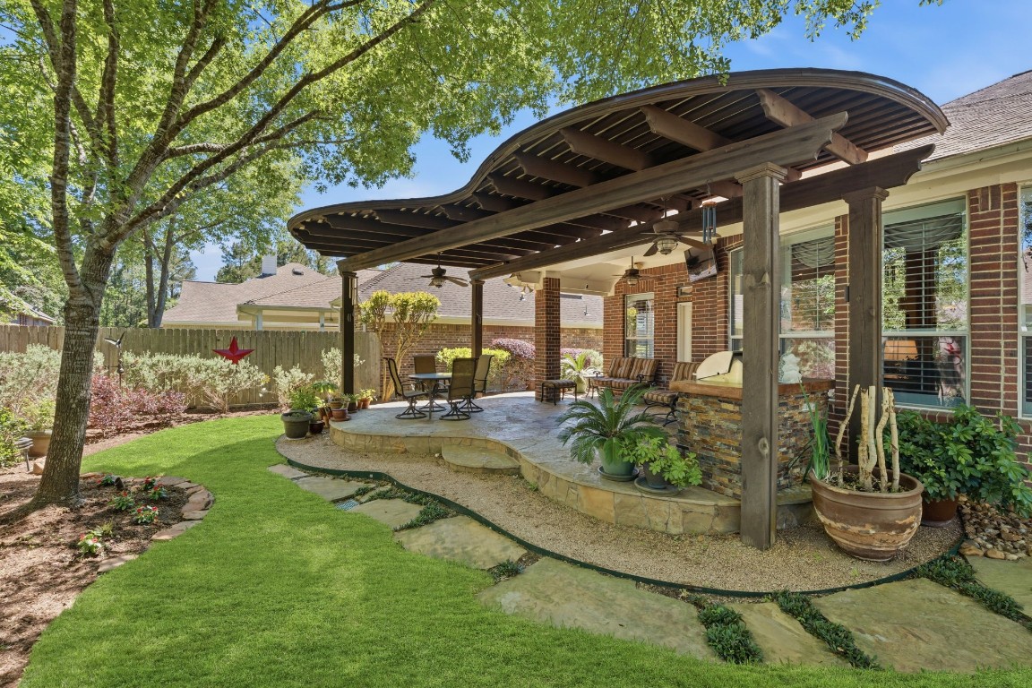 99 Bagpipe Way Conroe, TX 77384 - Photo 24 of 40 a view of a patio with table and chairs potted plants and large tree