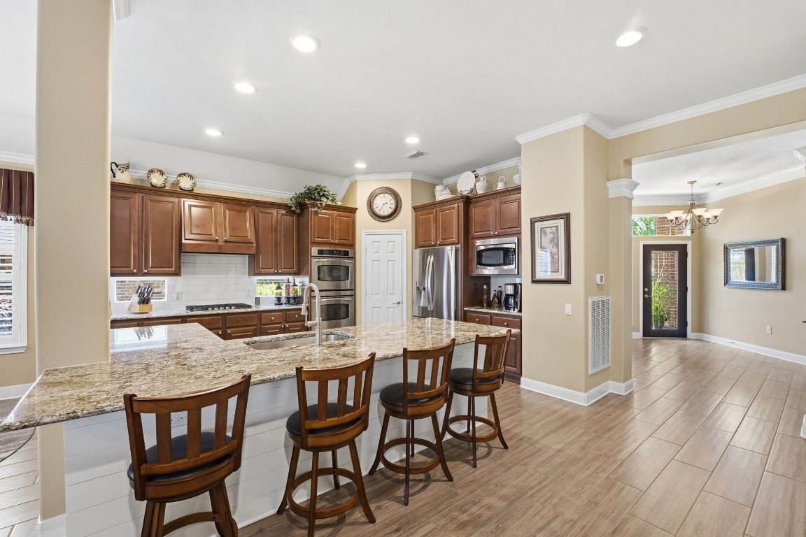 99 Bagpipe Way Conroe, TX 77384 - Photo 5 of 40 a kitchen with granite countertop a table chairs stove a sink and dishwasher