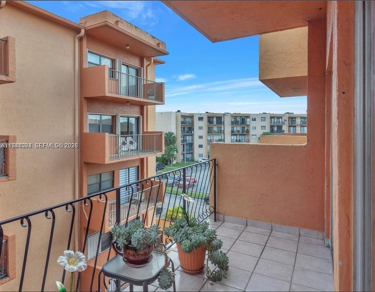 1900 West 54th Street, Unit 307 Hialeah, FL 33012 - Photo 5 of 7 a view of a balcony with chair and potted plants