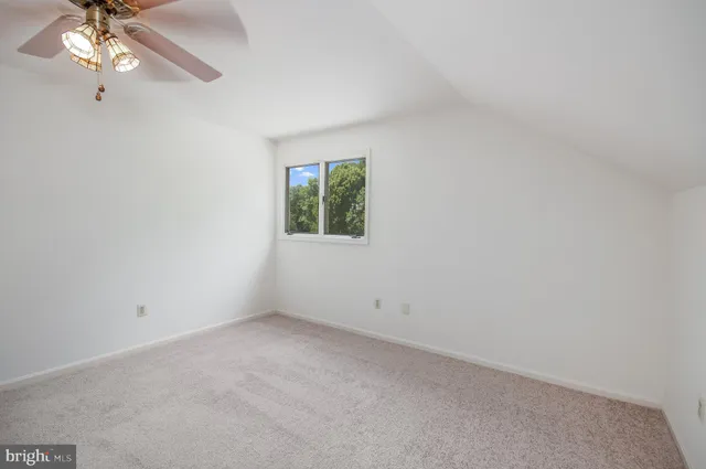 an empty room with a chandelier fan and windows
