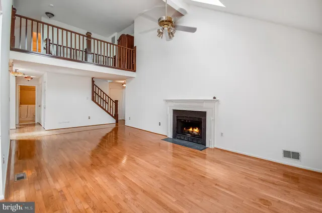 a view of an empty room with wooden floor and a fireplace