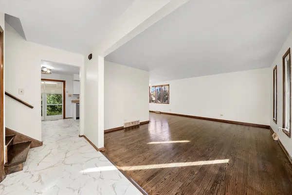 a view of an empty room with wooden floor and window
