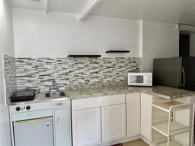 a kitchen with granite countertop white cabinets and white appliances