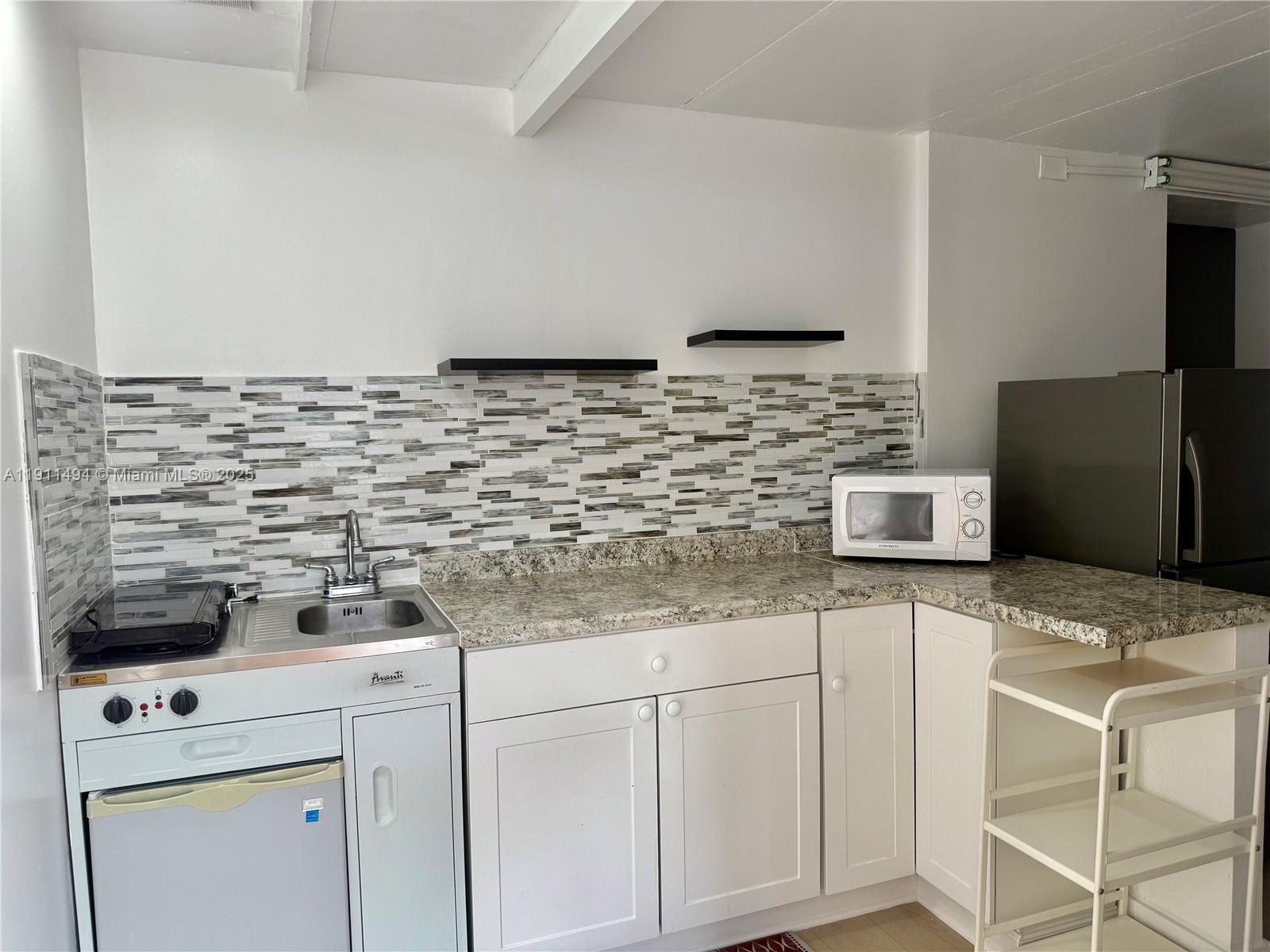 13008 Southwest 50th Lane, Unit 13008 Miami, FL 33175 - Photo 3 of 12 a kitchen with granite countertop white cabinets and white appliances