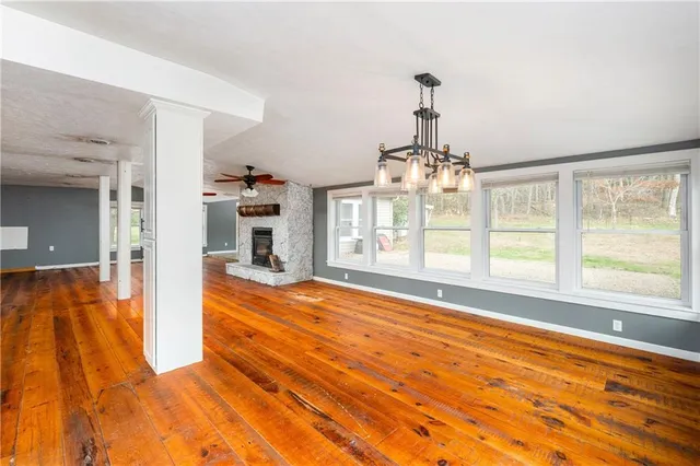 a view of an empty room with wooden floor and a fireplace