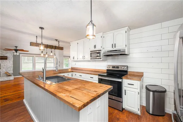 a kitchen with stainless steel appliances granite countertop a sink a stove and a wooden floors