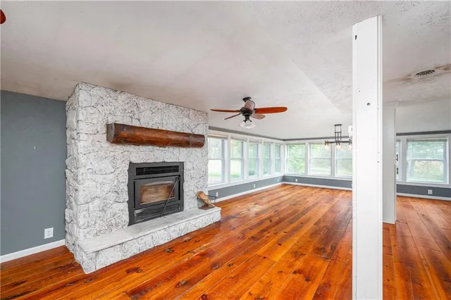a view of an empty room with wooden floor fireplace and a window