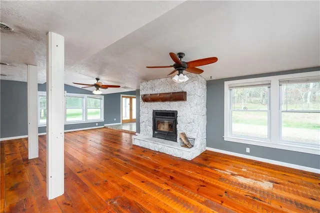 a view of an empty room with wooden floor fireplace and a window