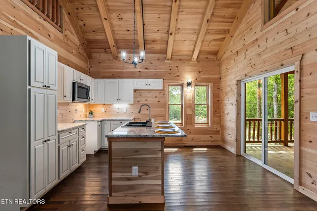 a kitchen with stainless steel appliances granite countertop a stove and wooden cabinets with wooden floor