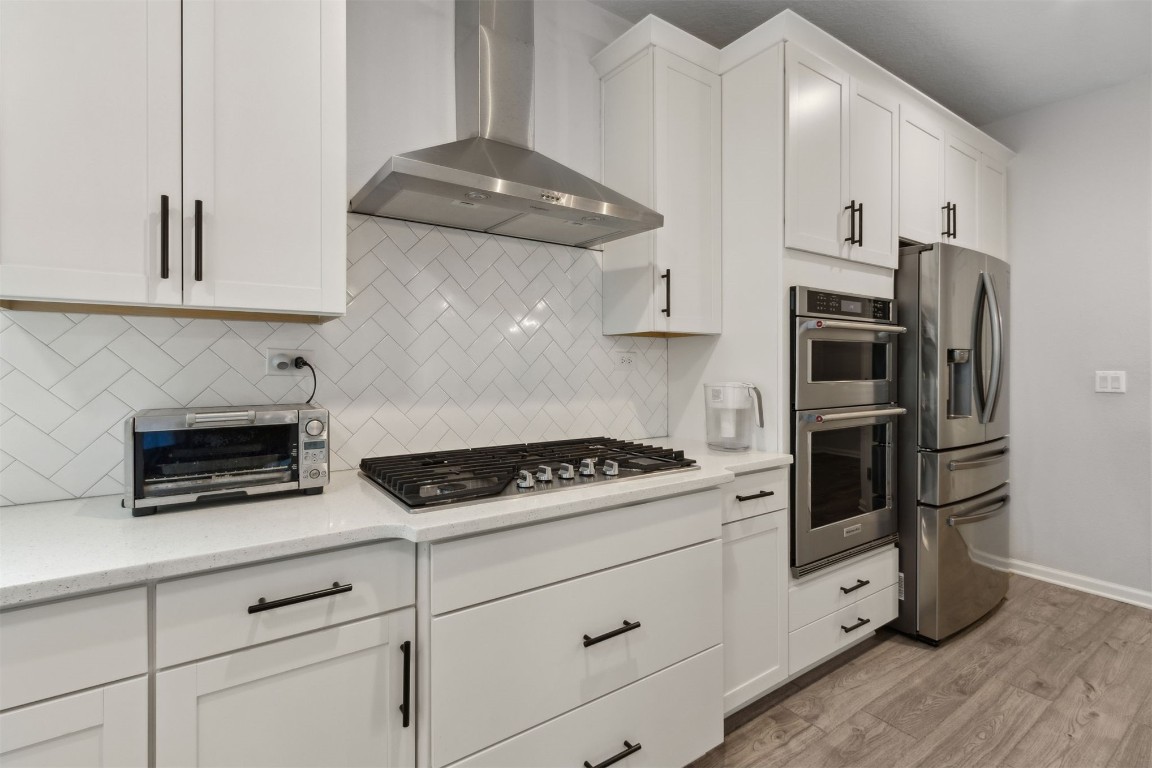 75251 White Rabbit Avenue Yulee, FL 32097 - Photo 21 of 83 a kitchen with stainless steel appliances granite countertop white cabinets and a stove a refrigerator with wooden floor