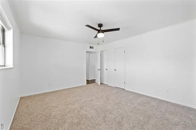 an empty room with a ceiling fan and window