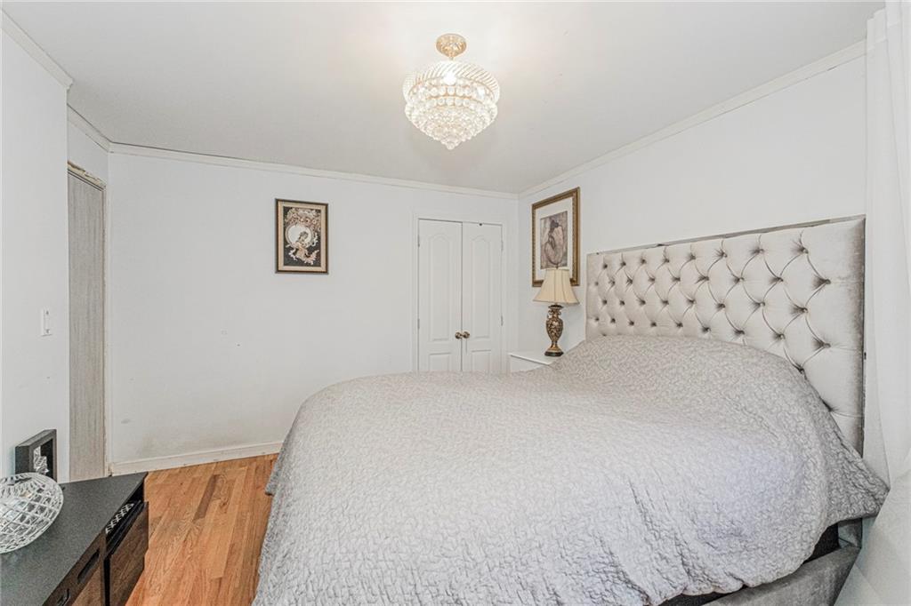 2809 East 28th Street, Unit 1C Brooklyn, NY 11235 - Photo 14 of 38 a bedroom with a bed and a chandelier