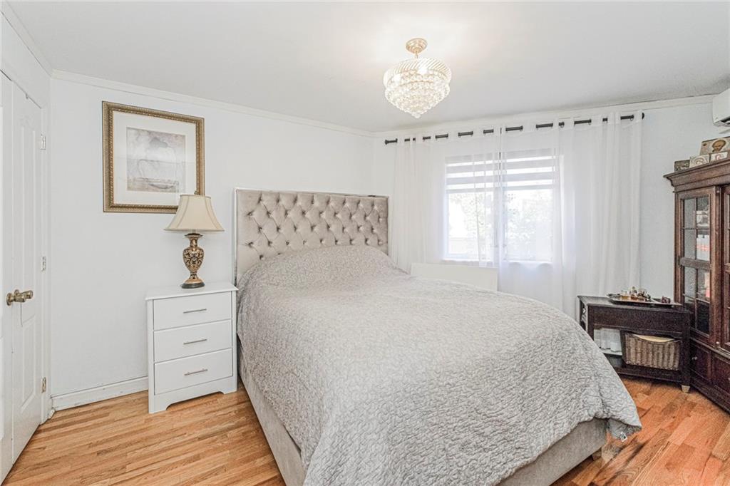 2809 East 28th Street, Unit 1C Brooklyn, NY 11235 - Photo 15 of 38 a bedroom with a bed and a chandelier