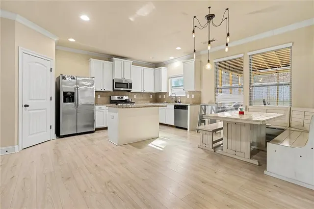 a kitchen with stainless steel appliances a sink a stove a refrigerator cabinets and wooden floor