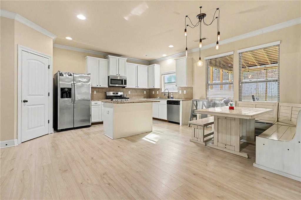 6791 Potomac Place Fairburn, GA 30213 - Photo 8 of 23 a kitchen with stainless steel appliances a sink a stove a refrigerator cabinets and wooden floor