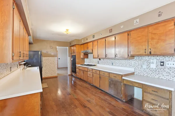 a large kitchen with stainless steel appliances a lot of counter space and a wooden floor