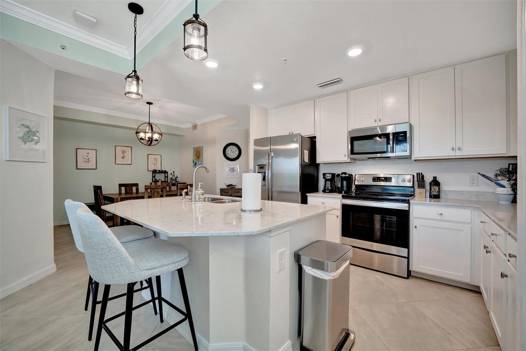 17724 Gawthrop Drive, Unit 101 Bradenton, FL 34211 - Photo 10 of 28 a kitchen with stainless steel appliances kitchen island a table chairs microwave and cabinets