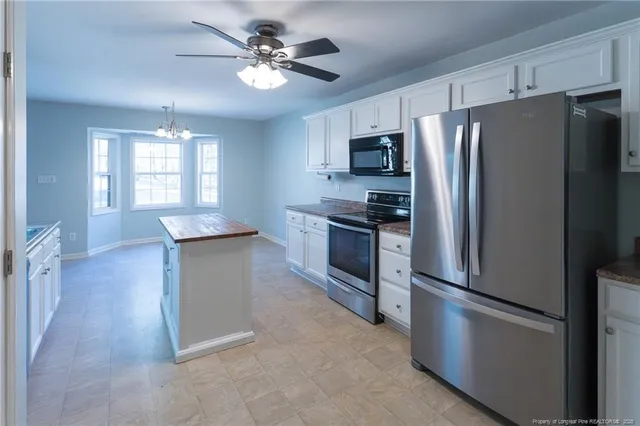 a kitchen with stainless steel appliances a refrigerator a stove a sink a center island and furniture