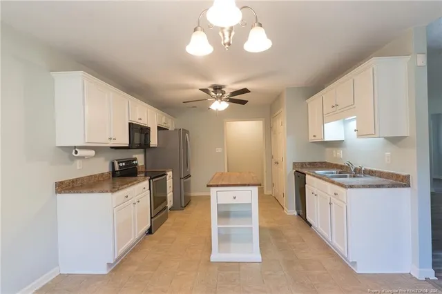 a kitchen with stainless steel appliances a stove top oven a sink a refrigerator cabinets and a dining table