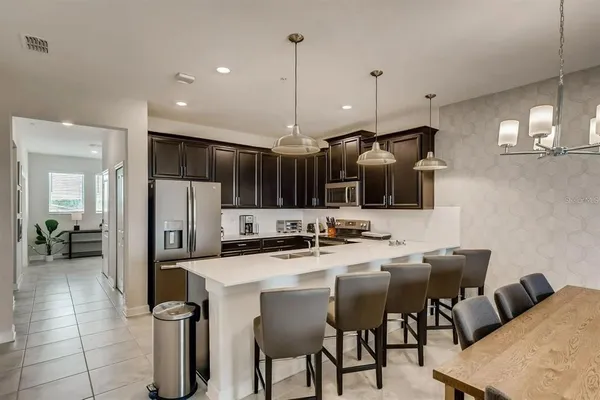 a kitchen with stainless steel appliances kitchen island granite countertop a sink a stove and chairs