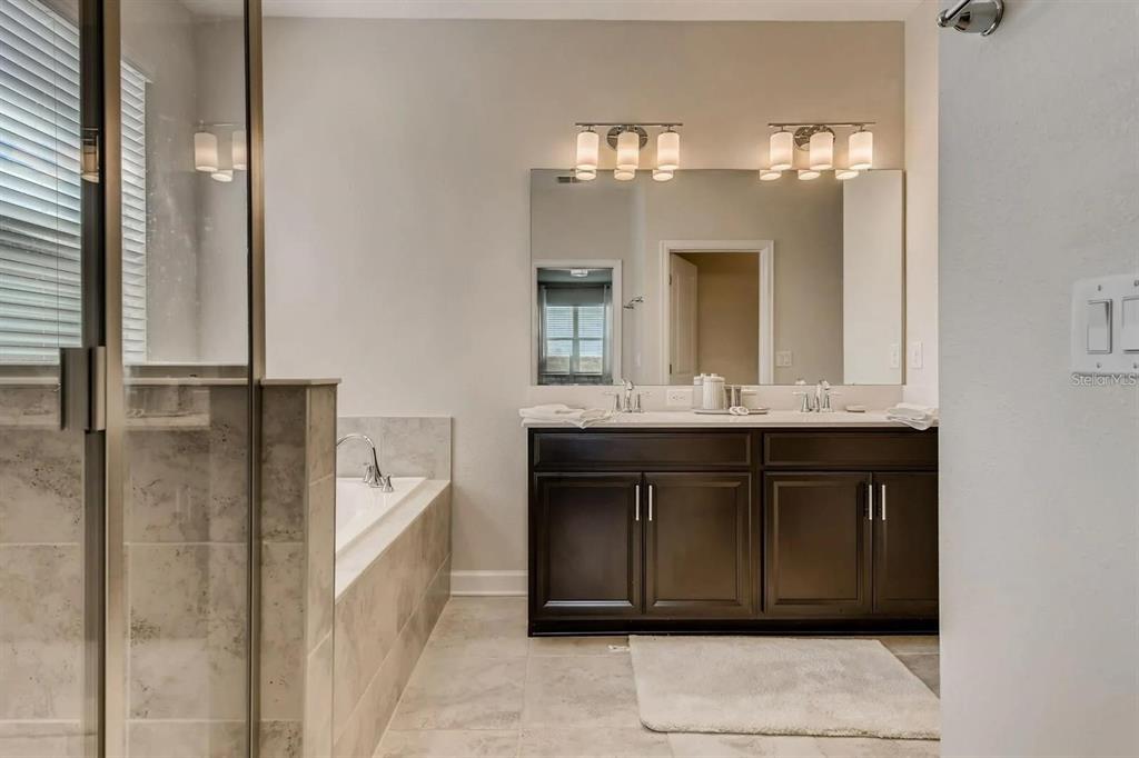 545 Ocean Course Avenue, Unit 545 Davenport, FL 33896 - Photo 20 of 32 a bathroom with a double vanity sink a mirror and a bathtub