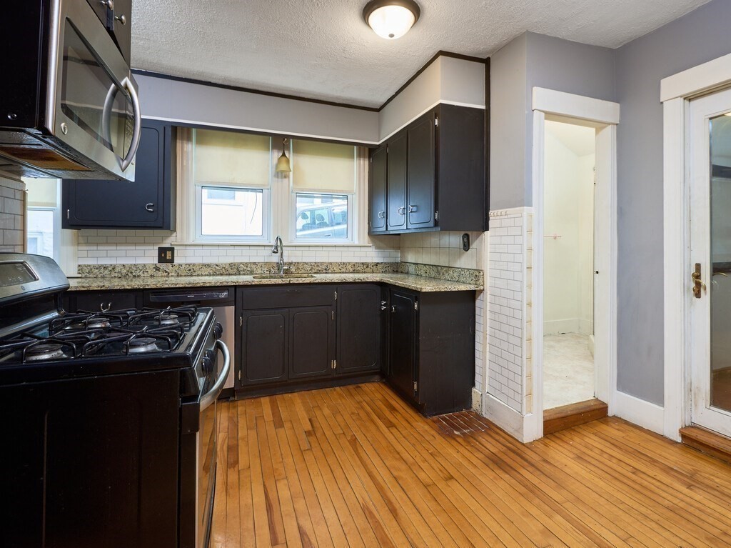 88 Beaconsfield Road Worcester, MA 01602 - Photo 11 of 34 a kitchen with stainless steel appliances granite countertop a stove a sink and a microwave