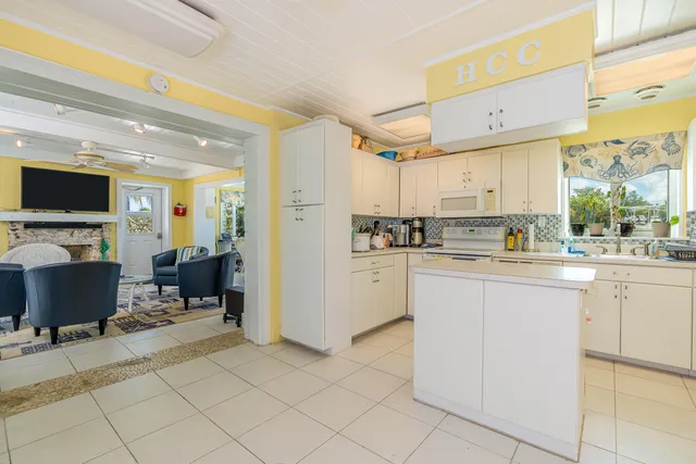 a dining room with wooden floor a chandelier a flat screen tv and a large window