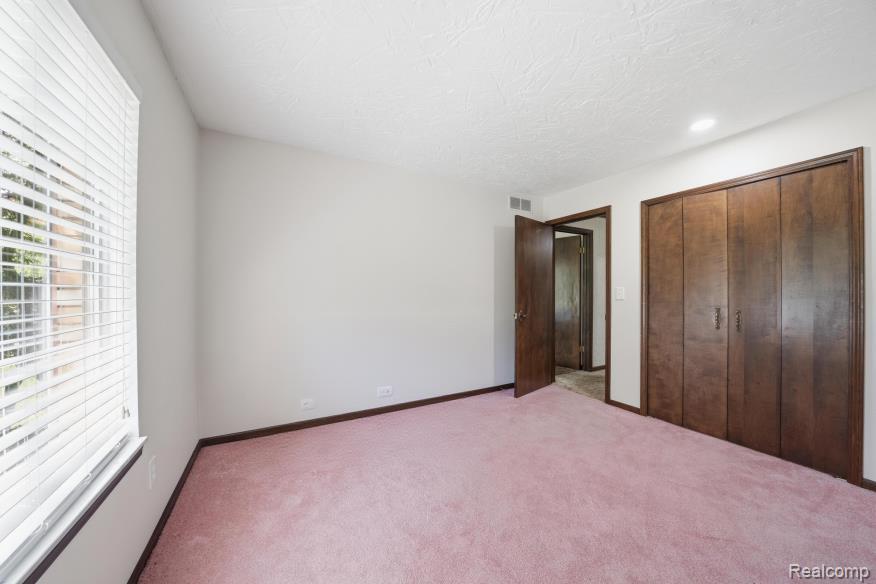 7020 Rattalee Lake Road Clarkston, MI 48348 - Photo 33 of 47 Spacious room featuring light-colored walls, dark wood-finish trim, and pink carpeting