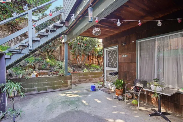 a view of a patio with table and chairs potted plants and a large tree
