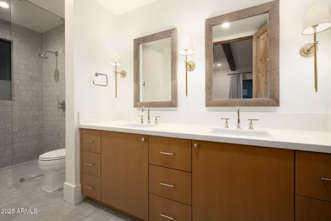 a bathroom with a double vanity sink toilet and mirror
