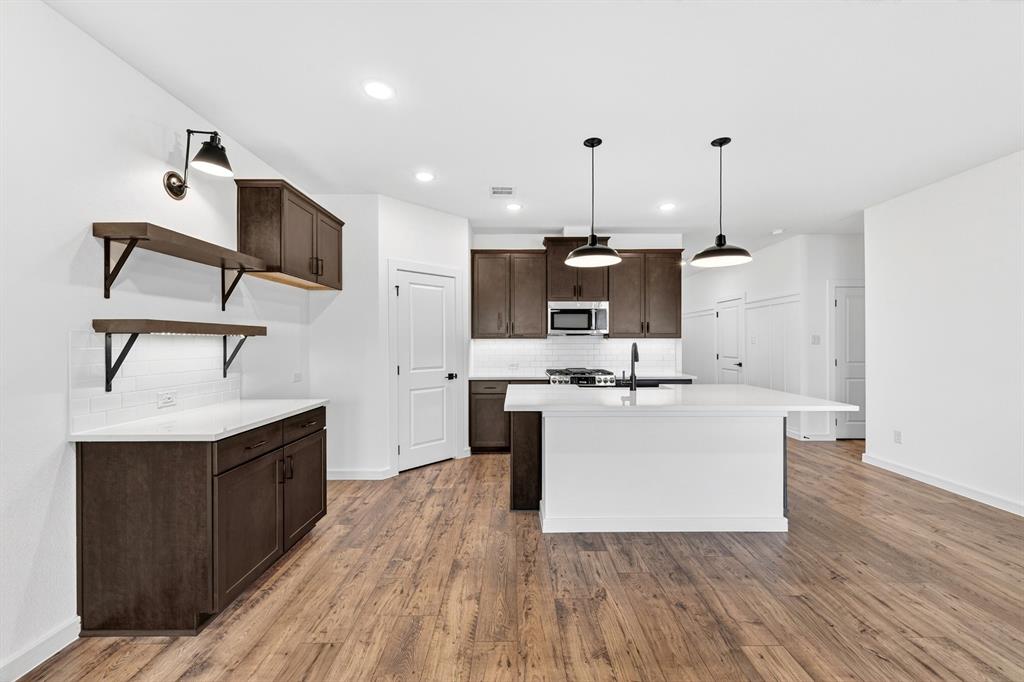 1313 Richardson Street Howe, TX 75459 - Photo 11 of 28 a living room with stainless steel appliances kitchen island a sink and wooden floor