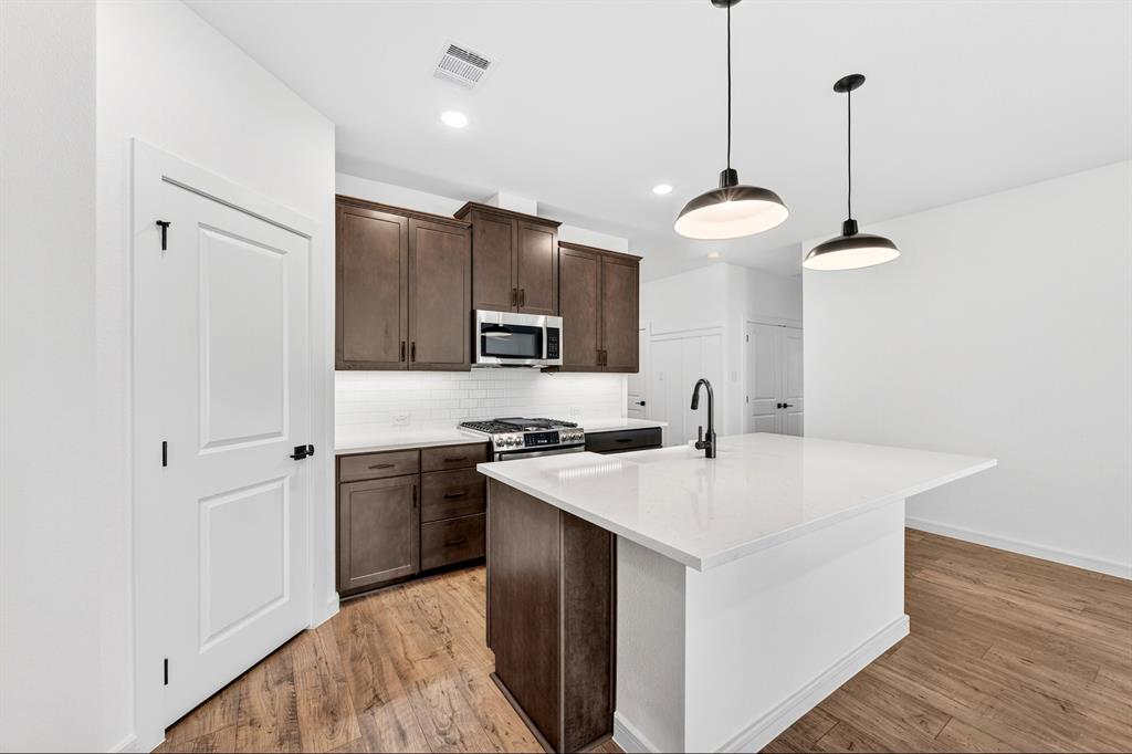 1313 Richardson Street Howe, TX 75459 - Photo 12 of 28 a kitchen with stainless steel appliances granite countertop a sink a stove a refrigerator and island with wooden floor