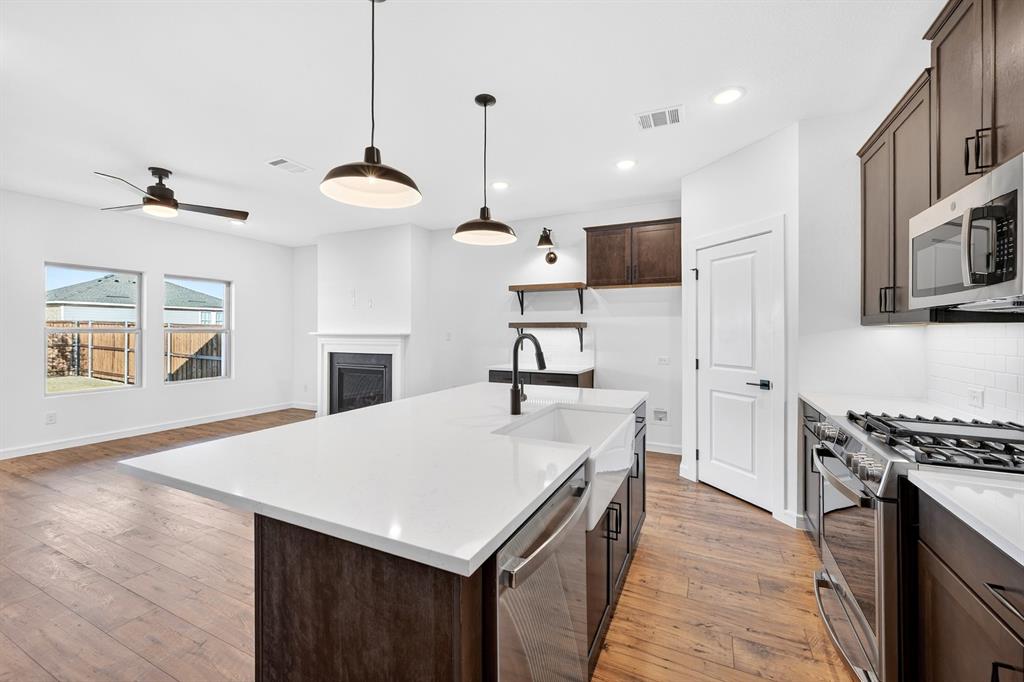 1313 Richardson Street Howe, TX 75459 - Photo 13 of 28 a kitchen with kitchen island a stove and a wooden floor