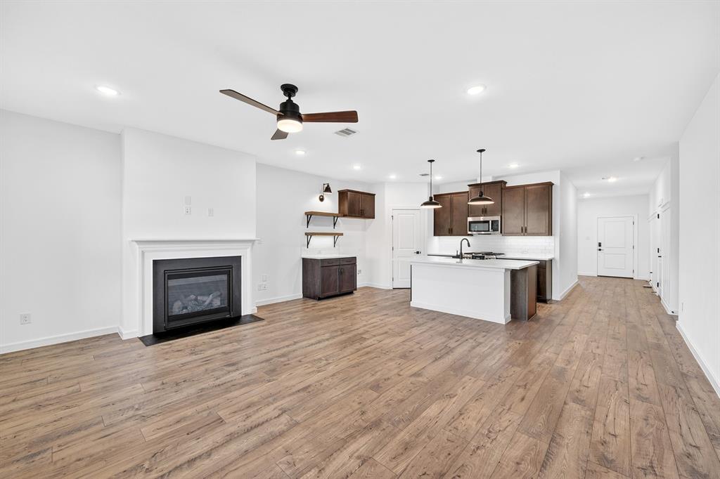1313 Richardson Street Howe, TX 75459 - Photo 6 of 28 a view of kitchen with microwave a stove top oven a sink and dishwasher with wooden floor