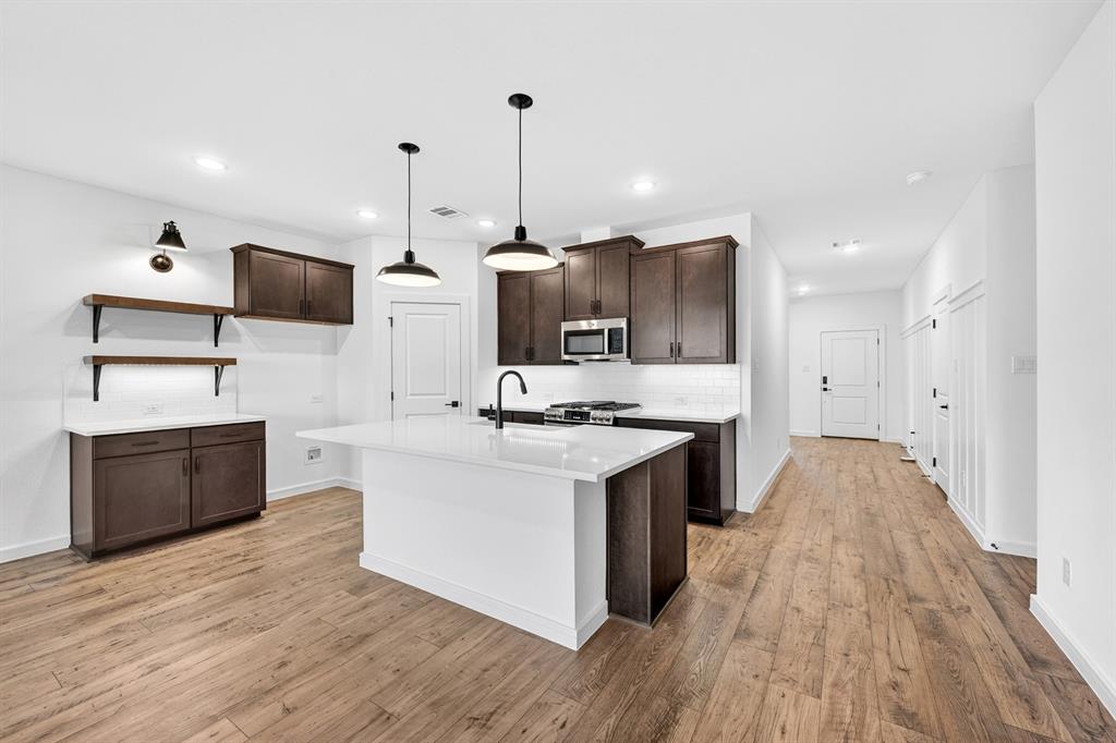 1313 Richardson Street Howe, TX 75459 - Photo 10 of 28 a large kitchen with stainless steel appliances granite countertop a stove and a wooden floors
