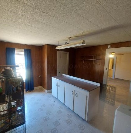 1608 Backus Street Paducah, TX 79248 - Photo 16 of 21 Kitchen featuring white cabinets, light floors, wooden walls, and dark countertops