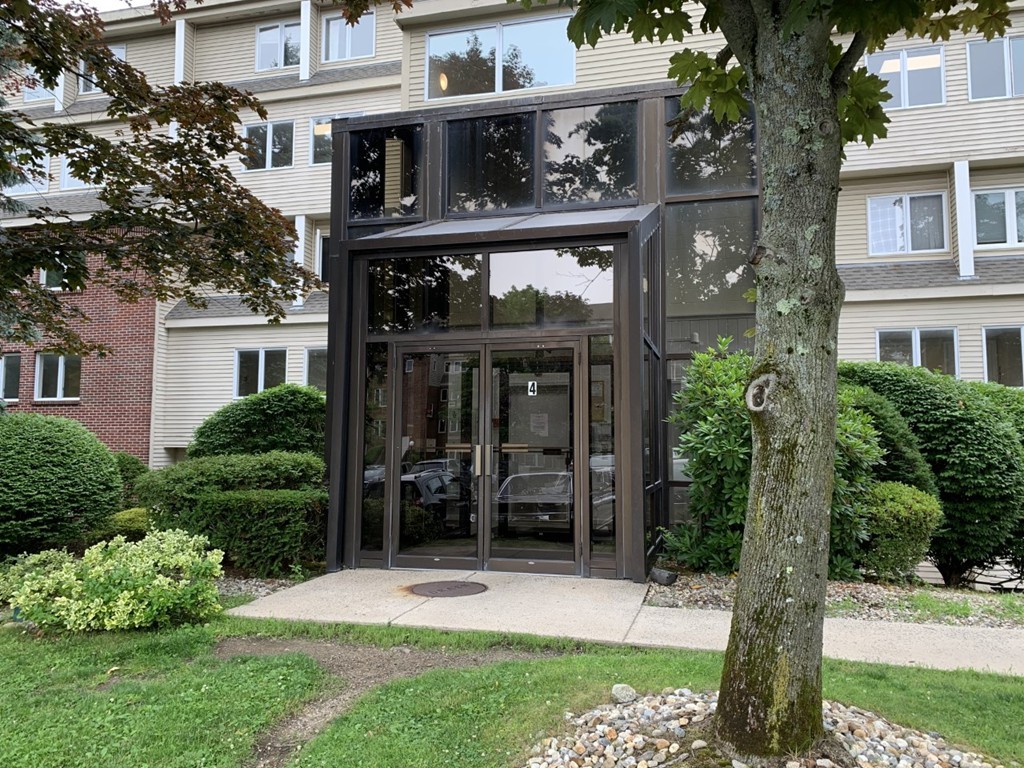 4 Duck Pond Road, Unit 204 Beverly, MA 01915 - Photo 4 of 23 a view of a house with brick walls and a yard with plants