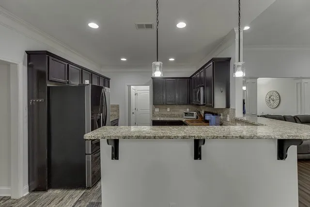 a kitchen with stainless steel appliances granite countertop a refrigerator a sink a stove a microwave and island