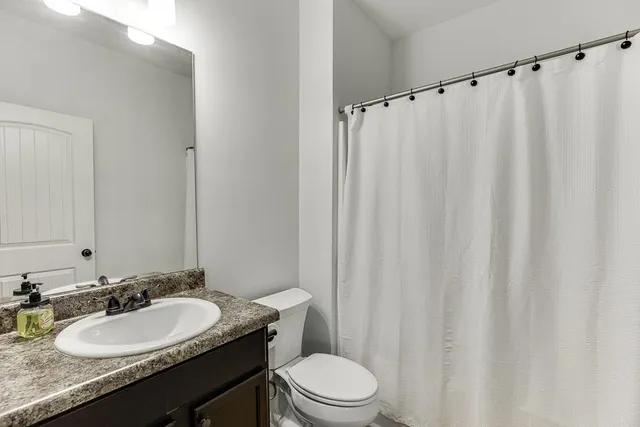 a bathroom with a granite countertop sink toilet and a mirror