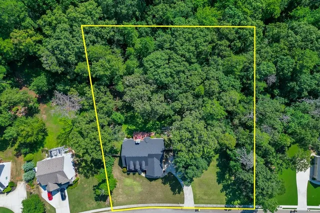 an aerial view of a houses with a yard and lake