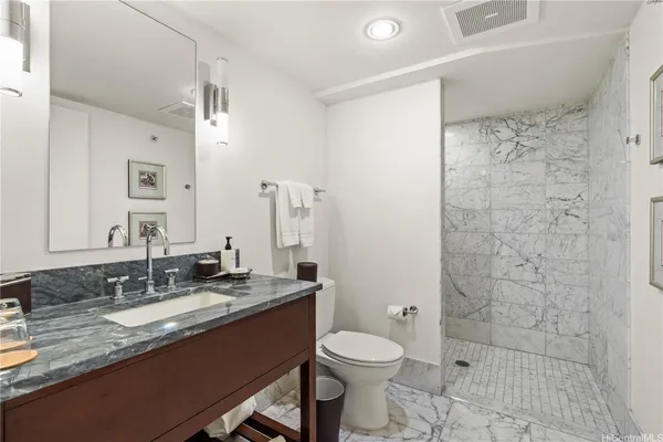a bathroom with a granite countertop sink a toilet a mirror and shower