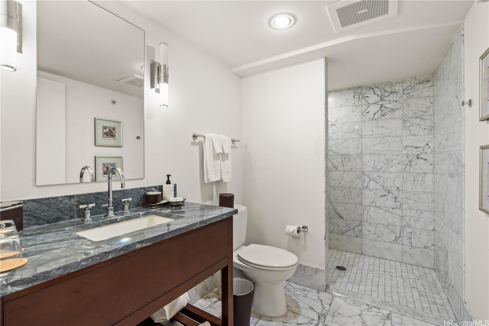 223 Saratoga Road, Unit 1115 Honolulu, HI 96815 - Photo 2 of 25 a bathroom with a granite countertop sink a toilet a mirror and shower