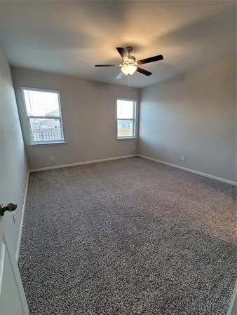 an empty room with a chandelier fan and windows