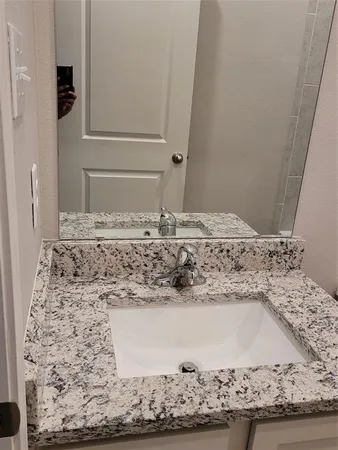 a bathroom with a granite countertop sink and a mirror